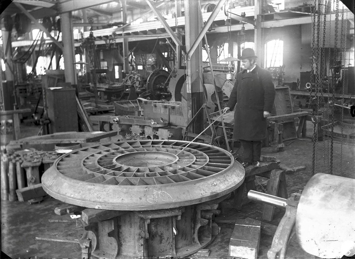 Administrerende direktør Fredrik Hiorth peker på et turbinhjul med stokken sin. Kværner Brug en gang mellom 1890 og 1920. Foto: Ukjent person/Norsk Teknisk Museum