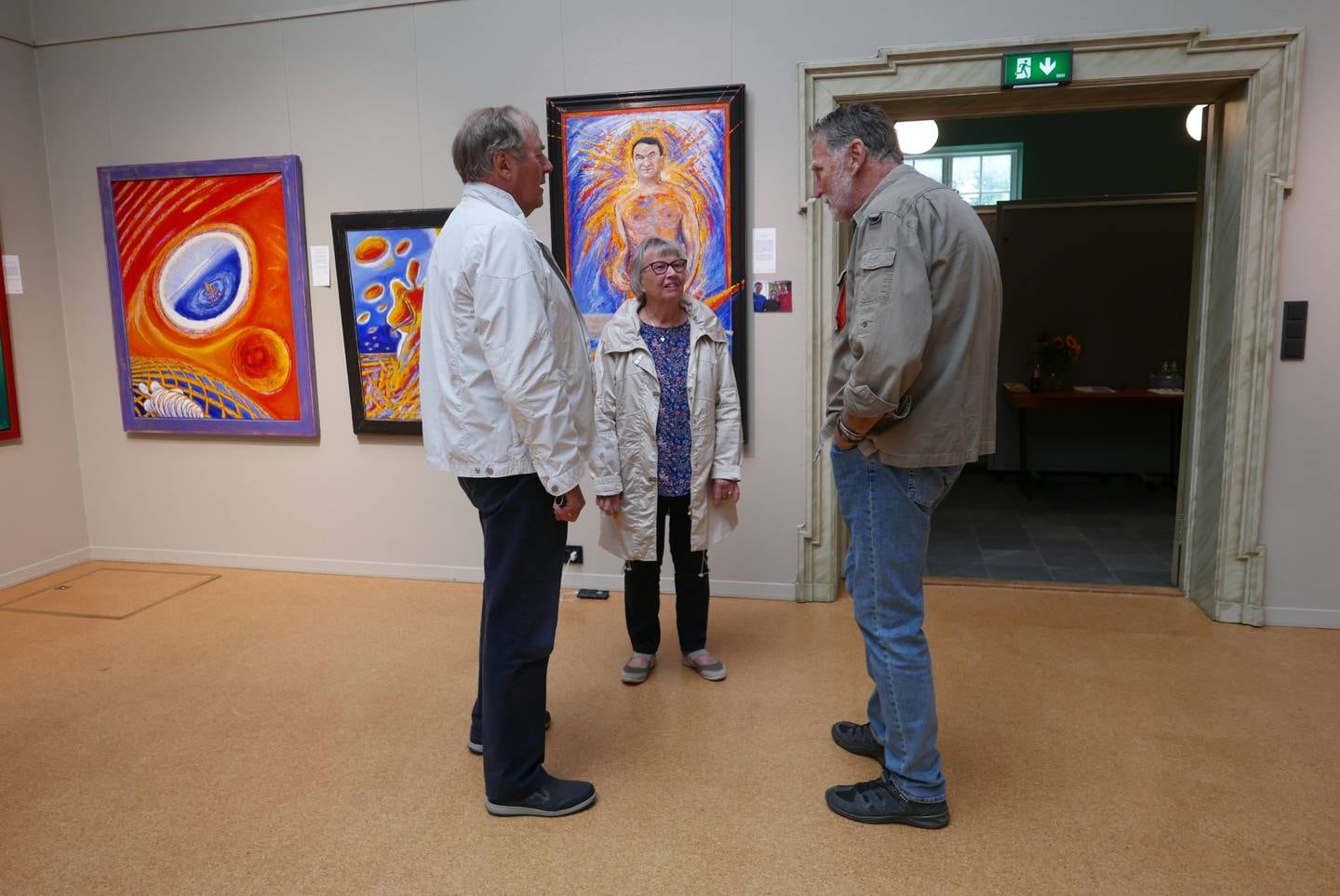 Bengt Børresen snakker med to besøkende på hans utstilling Fabulizmer i Overlyssalen på Fredrikstad Bibliotek