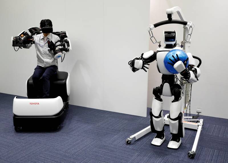 An employee of Toyota Motor Corp. demonstrates a T-HR3 humanoid robot which will be used to support the Tokyo 2020 Olympic and Paralympic Games, during a press preview in Tokyo, Japan July 18, 2019. Picture taken July 18, 2019.  REUTERS/Issei Kato