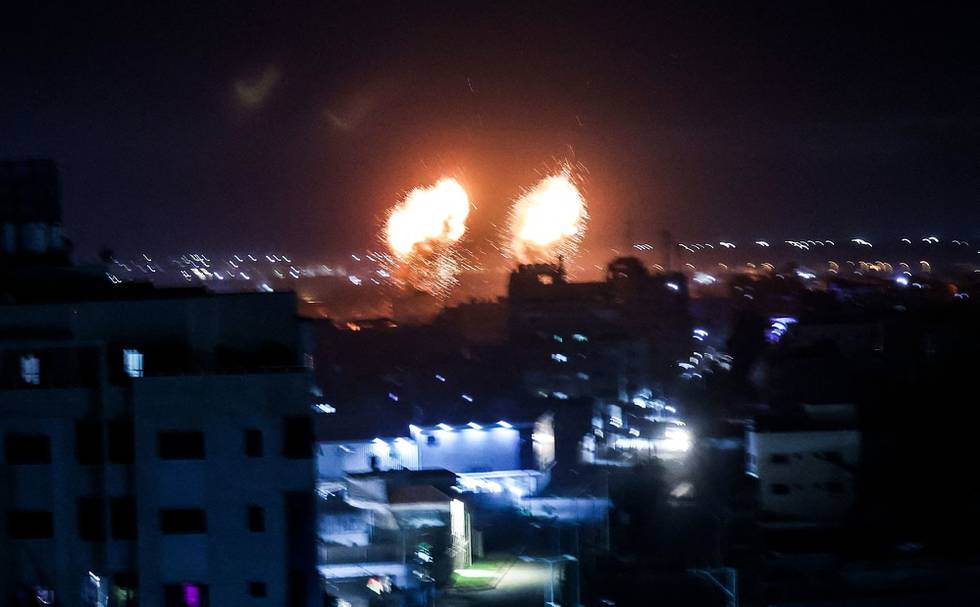 Explosions light-up the night sky above buildings in Gaza City as Israeli forces shell the Palestinian enclave, early on June 16, 2021. (Photo by Mahmud hams / AFP)