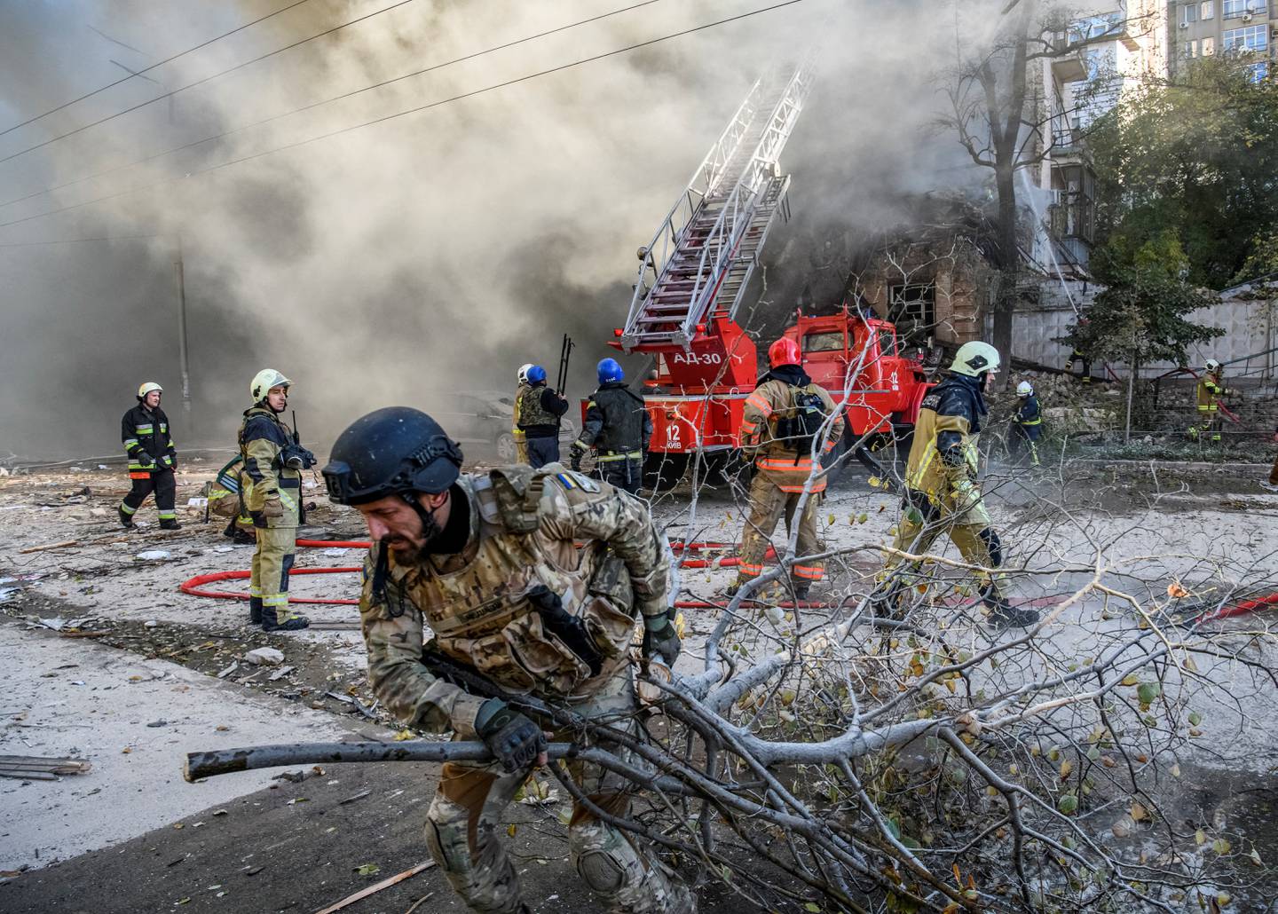 Brannmannskaper i Kyiv forsøker å evakuere en kvinne som befinner seg i en boligblokk som skal ha blitt truffet av en drone.