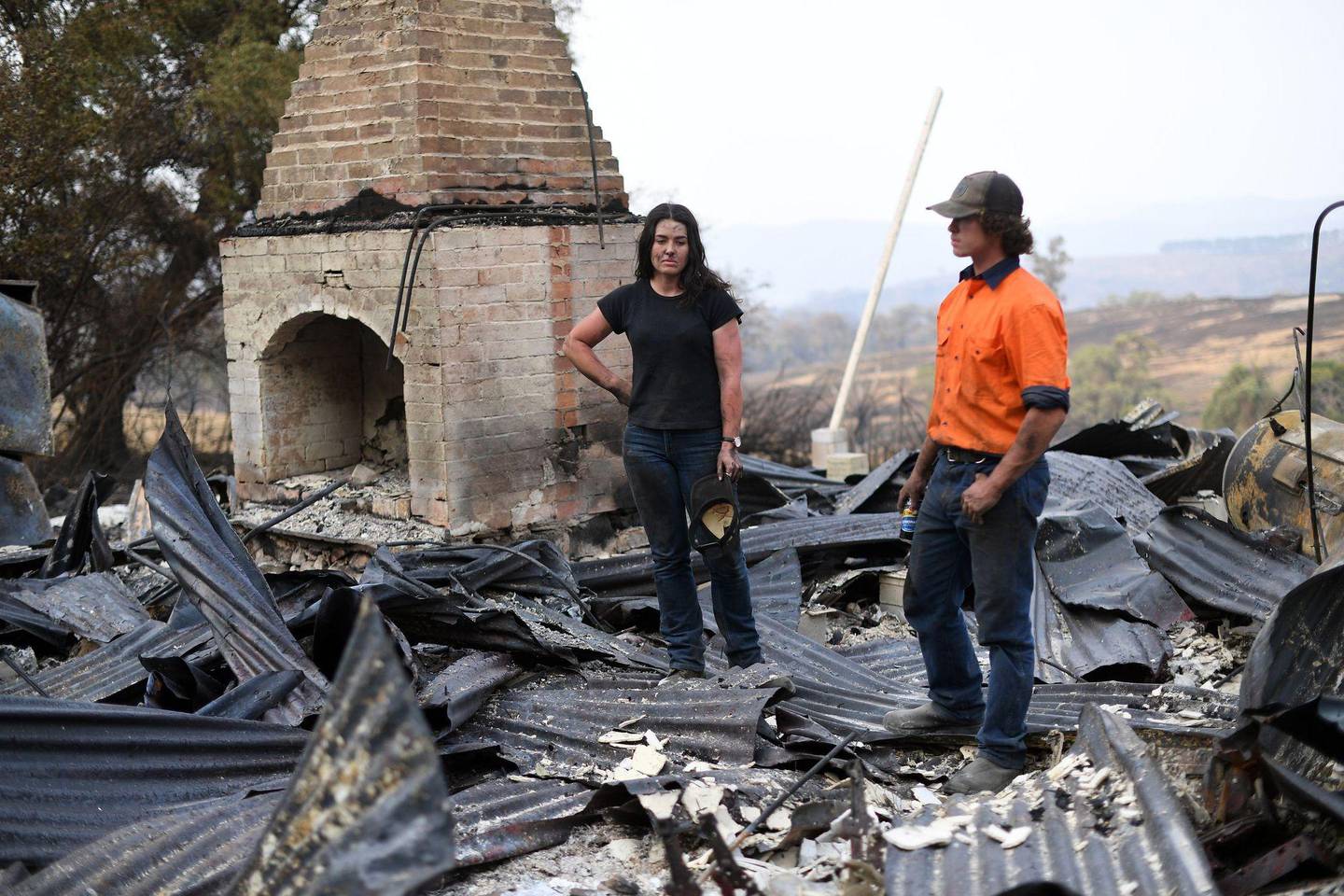 This photo taken on January 8, 2020 shows Kiahan Bellchambers (L) and her brother Jesse Bellchambers looking for belongings amongst the ruins of their house destroyed during bushfires in Batlow, in Australia's New South Wales state. - Batlow has become one of the faces of the destruction wrought by the unprecedented disaster, which also hit areas usually untouched with Australia's summer fires, when shocking images of dead livestock along a road was shared by the national broadcaster ABC. (Photo by SAEED KHAN / AFP) / To go with AFP story Australia-fire-climate-environment, SCENE by Glenda KWEK