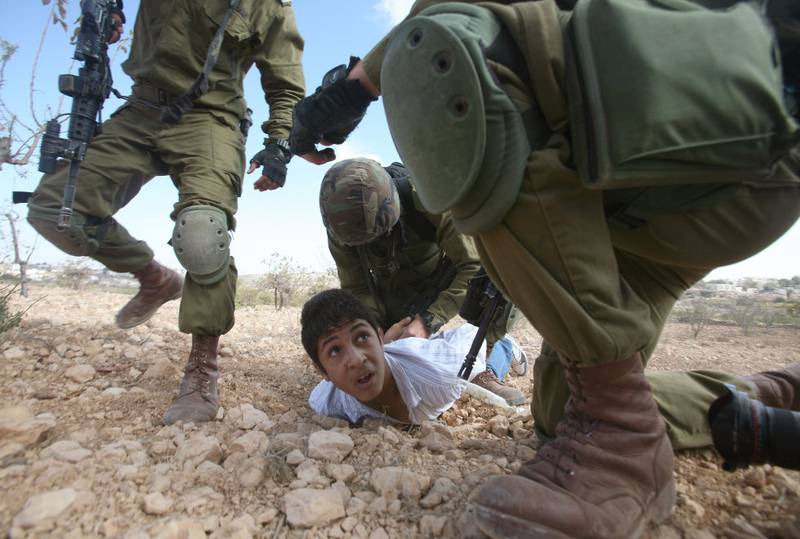 Palestinske barn forskjellsbehandles når de stilles for militærdomstol for å ha kastet steiner, mens israelske barn blir stilt for vanlig, israelsk rett, sier den israelske forsvarsadvokaten Nery Ramati. Bildet viser en palestinsk gutt som blir arrestert av israelske soldater for å ha kastet stein, under en protest mot en jødisk bosetning i 2010.