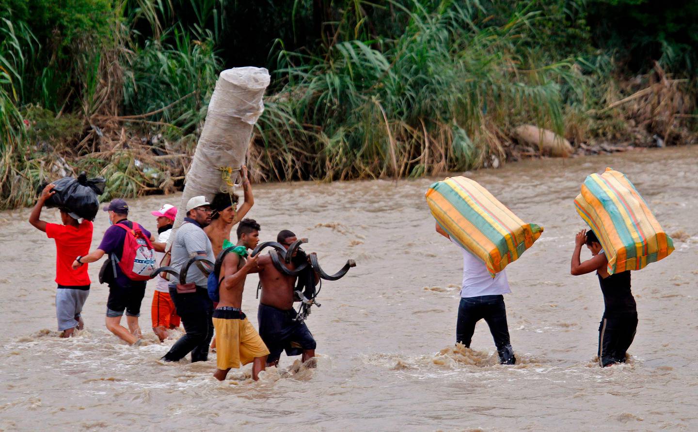 Migrants cross the Tachira river, the natural border between Colombia and Venezuela, as the official border remains closed due to the COVID-19 pandemic in Cucuta, Colombia, on November 19, 2020. - Hundreds of Venezuelans stranded in Colombia tried to cross the international bridge Wednesday as heavy rains had increased the river level. (Photo by Schneyder MENDOZA / AFP)