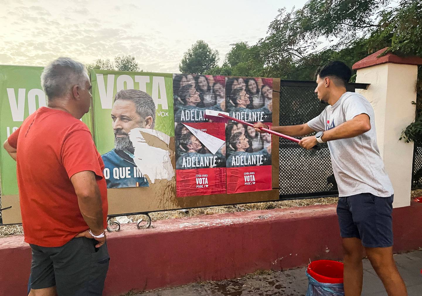 Valgkampplakater med bilde av statsminister Pedro Sanchez henges opp ved siden av plakater av Vox-leder Santiago Abascal.