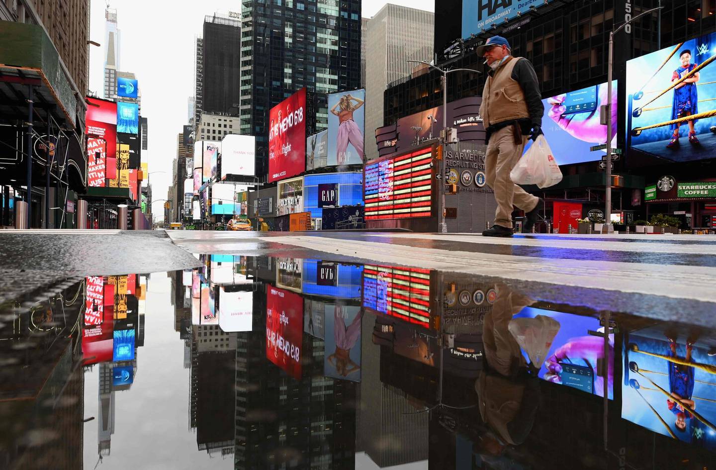 A man crosses the street at a nearly empty Time Square on April 09, 2020 in New York City. - Another 6.6 million US workers file for unemployment benefits for the week ending April 4, 2020, the Labor Department said on April 9, 2020, a slight decrease from the previous week's count of 6.9 million, which was 219,000 more than the original tally, according to the report. Nearly 17 million workers lost their jobs since mid-March, as the coronavirus pandemic continues to affect the economy. (Photo by Angela Weiss / AFP)