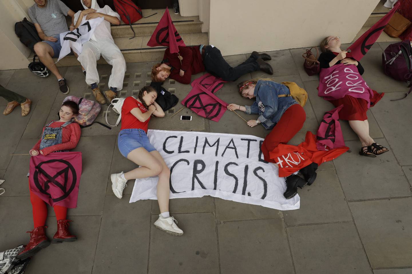 Extinction Rebellion climate change protesters stage a die-in outside the Royal Opera House to demand that they drop oil producer BP as a sponsor, in central London, Tuesday, July 2, 2019. (AP Photo/Matt Dunham)