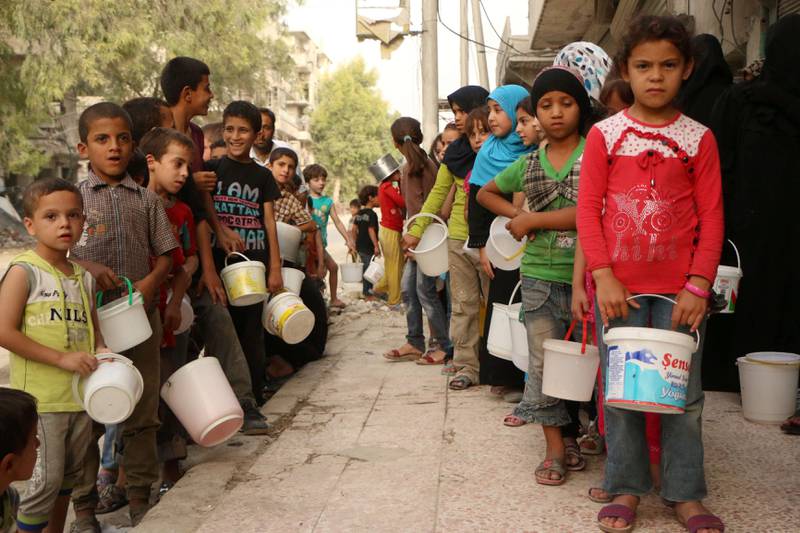 Barn utenfor byen Aleppo i Syria venter i vannkø. Over 7 millioner syrere har blitt flyktninger i eget land. FOTO: NTB SCANPIX