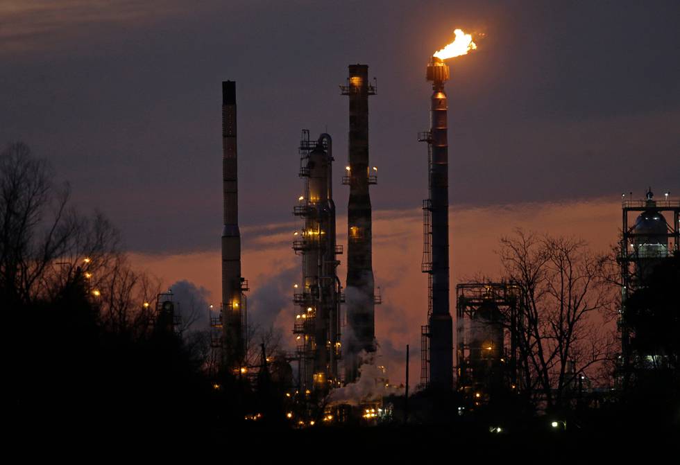 FILE - In this Feb. 13, 2015, file photo, stacks and burn-off from the Exxon Mobil refinery are seen at dusk in St. Bernard Parish, La. Corporate America has a profit problem. U.S company earnings are falling for the first time since 2009, when the economy was still reeling from the Great Recession. The main culprit is the plunging price of oil, which has decimated earnings at big energy companies like Exxon Mobil and Chevron. (AP Photo/Gerald Herbert, File)