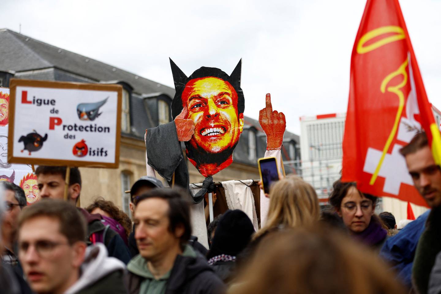 Demonstranter i Paris 15. mars holder opp en plakat som skal forestille president Emmanuel Macron.