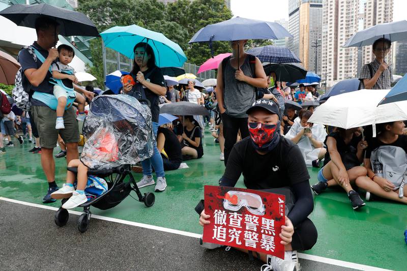 A protester holds up a card which reads "Thoroughly examine corrupt police, Investigate police brutality" during a rally in Hong Kong on Sunday, Aug. 18, 2019. A spokesman for China's ceremonial legislature condemned statements from U.S. lawmakers supportive of Hong Kong's pro-democracy movement, as more protests were planned Sunday following a day of dueling rallies that highlighted the political divide in the Chinese territory. (AP Photo/Vincent Thian)