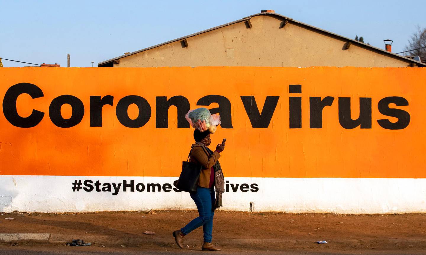 FILE - In this June 19, 2020, file photo, a woman wearing a face mask passes a coronavirus billboard carrying a message in a bid to prevent the spread of the virus. South Africas reported coronavirus are surging. Its hospitals are now bracing for an onslaught of patients, setting up temporary wards and hoping advances in treatment will help the countrys health facilities from becoming overwhelmed. (AP Photo/Themba Hadebe, File)