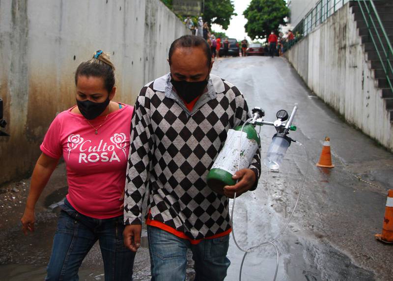 Accompanied by his wife, Rafael Pereira carries an oxygen tank that bought for his mother in law, who is hospitalized with COVID-19, amid the new coronavirus pandemic at the at the 28 Agosto Hospital, in Manaus, Brazil, Thursday, Jan 14, 2021. Scores of COVID-19 patients in the Amazon rainforest's biggest city will be transferred out of state as the local health system collapses and dwindling stocks of oxygen tanks begin to falter. (AP Photos/Edmar Barros)