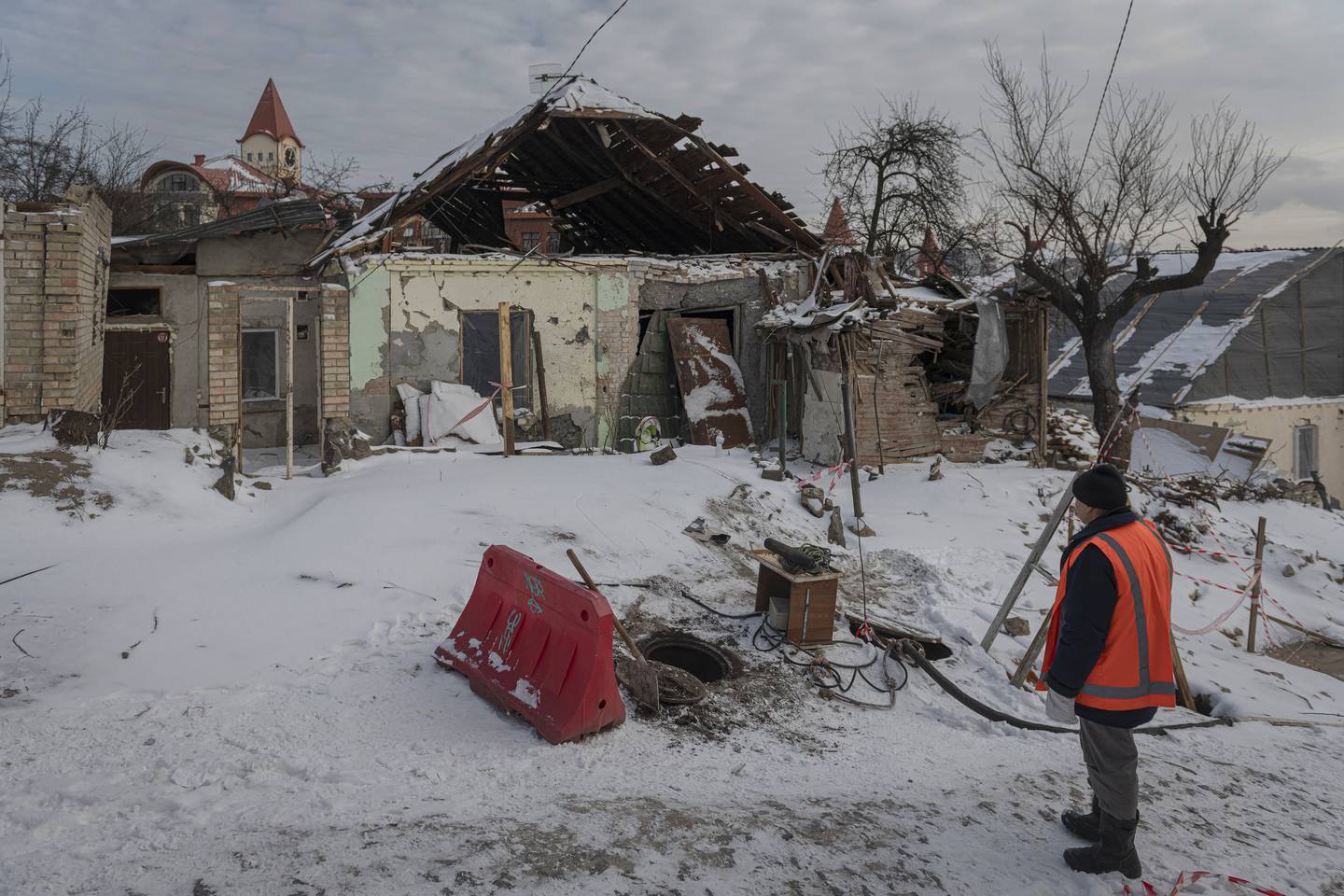 En offentlig ansatt i ferd med å rydde ved en bygning ødelagt av russiske rakettangrep i Kyiv i januar 2023.