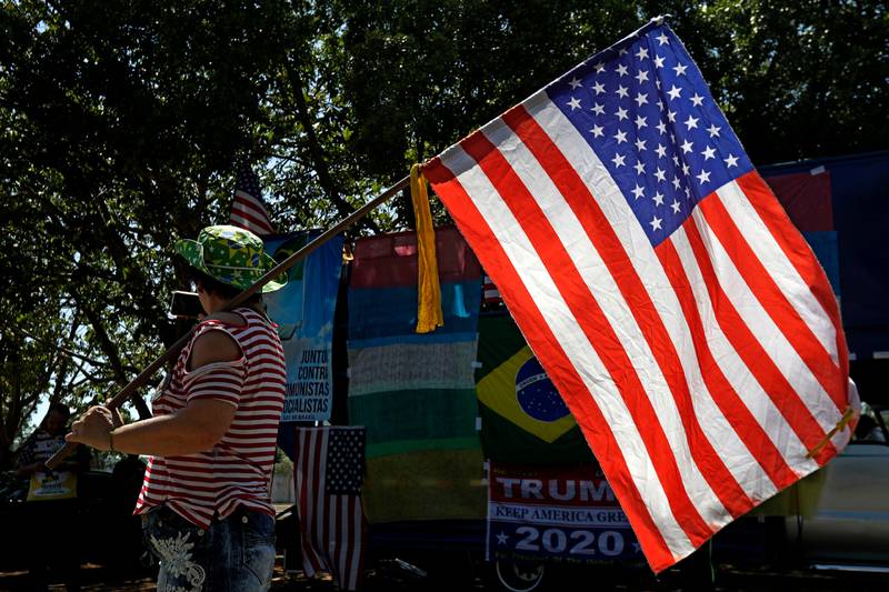 A demonstrator makes a selfie with the American flag, during a protest called "Go Trump, Go" in support of US President Donald Trump and his re-election, in front of the American embassy in Brasilia, Brazil, Sunday, Oct. 4, 2020. (AP Photo/Eraldo Peres)