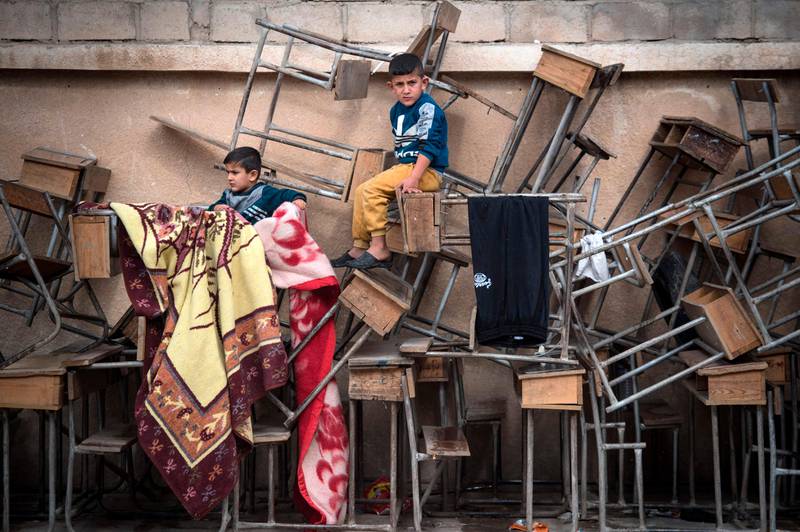TOPSHOT - Displaced Syrian children sit on classroom tables at a school turned into a shelter for people displaced by the war, in the northeastern Syrian town of Hasakeh, on October 24, 2019. - Turkey and its Syrian proxies on October 9 launched a cross-border attack against Kurdish-held areas, grabbing a 120-kilometre (70-mile) long swathe of Syrian land along the frontier. The deadly incursion killed hundreds and caused 300,000 people to flee their homes in the latest humanitarian disaster in Syria's gruelling eight-year war. (Photo by Fadel SENNA / AFP)