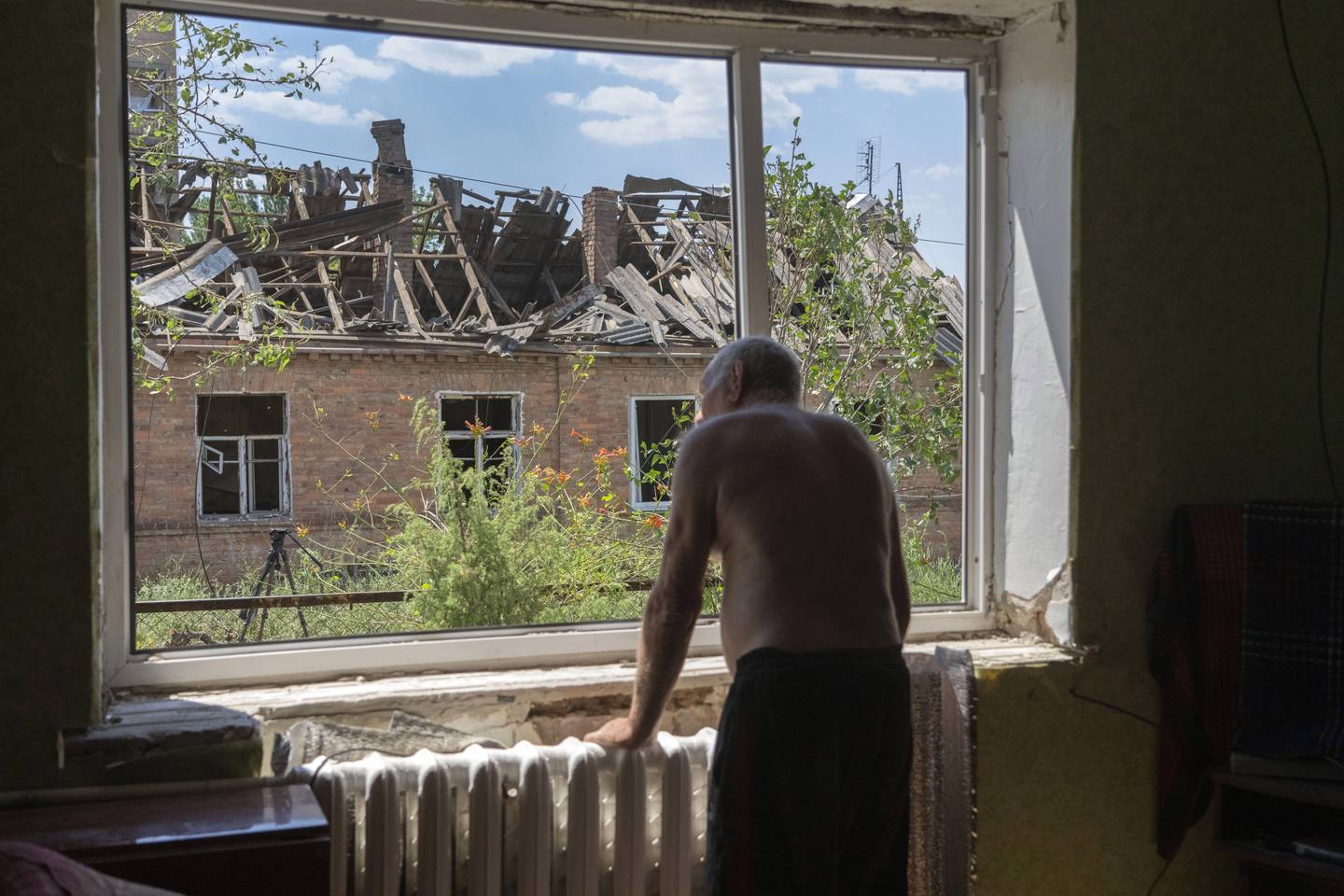 Victor Rosenberg (81) ser ut av vinduet etter at det ble ødelagt i et russisk angrep mot Bakhmut sentrum i juli i fjor. Arkivfoto: Efrem Lukatsky / AP / NTB