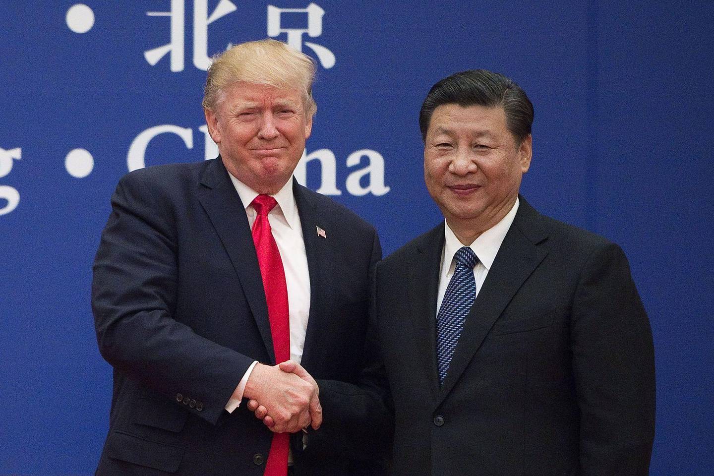 (FILES) This file photo taken on November 9, 2017 shows US President Donald Trump (L) and China's President Xi Jinping shaking hands during a business leaders event at the Great Hall of the People in Beijing. - Donald Trump's first term in office has been rough on China, with war over trade and tech amplified by daily mudslinging, yet Beijing may welcome his re-election as it scans the horizon for the decline of its superpower rival. (Photo by Nicolas ASFOURI / AFP) / TO GO WITH US-vote-diplomacy-trade-China,FOCUS by Patrick Baert