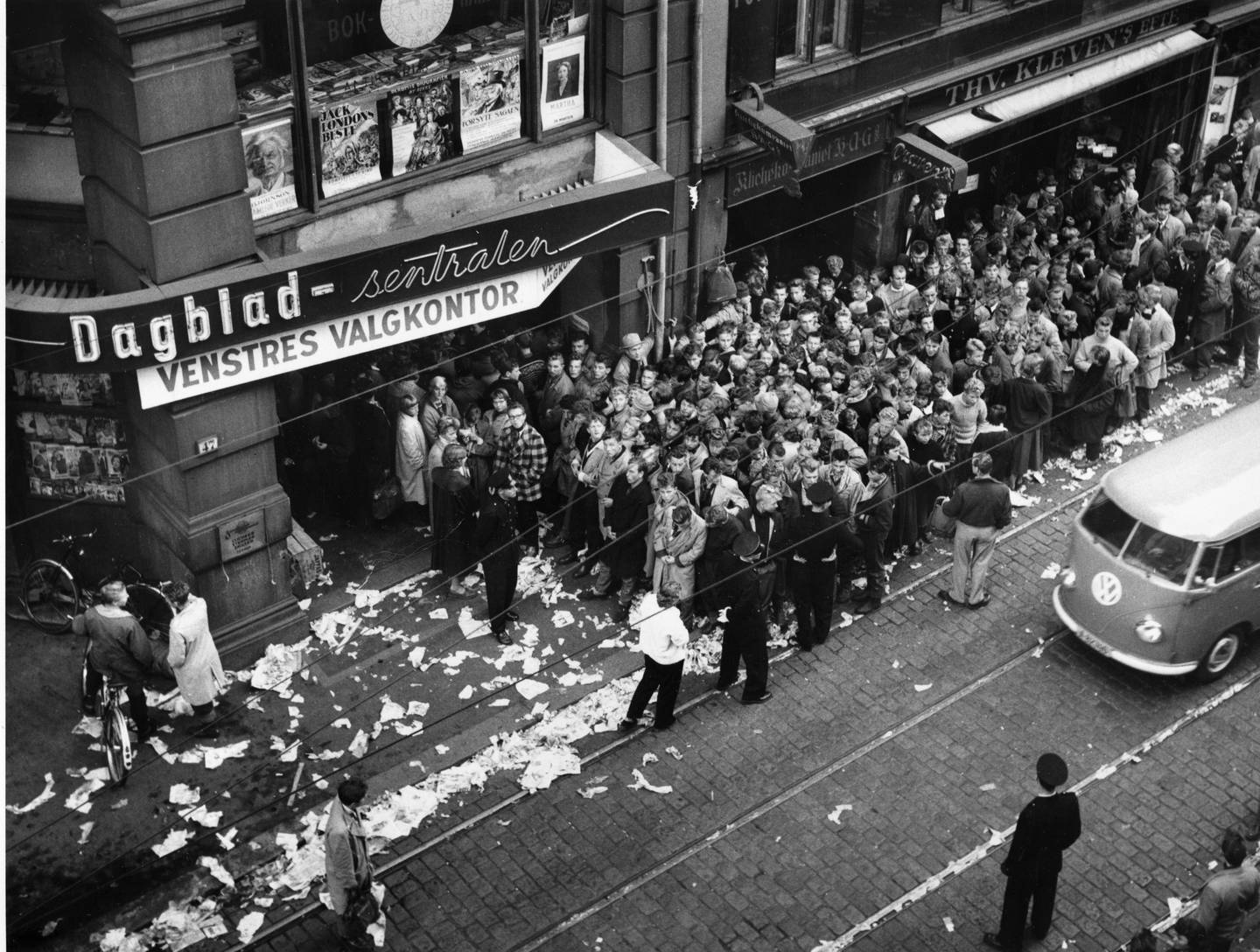 Folk i lange køer utenfor Dagblad-sentralen for å sikre seg billetter til Louis Armstrongs konsert i oktober 1955. Mange hadde ventet hele natten, noe søppel og papir i gata vitner om.