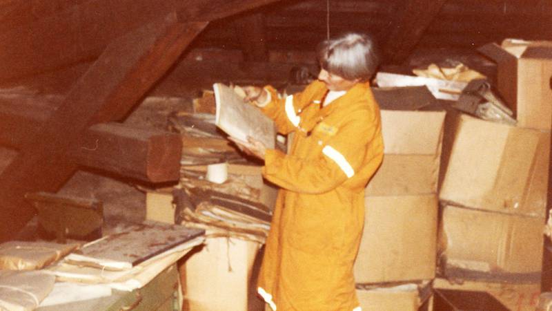 Kommunearkivar Marcia Berg studerer etterlatt arkivmateriale på et loft i Storgata, juni 1985. Kommunen trengte nytt arkiv!