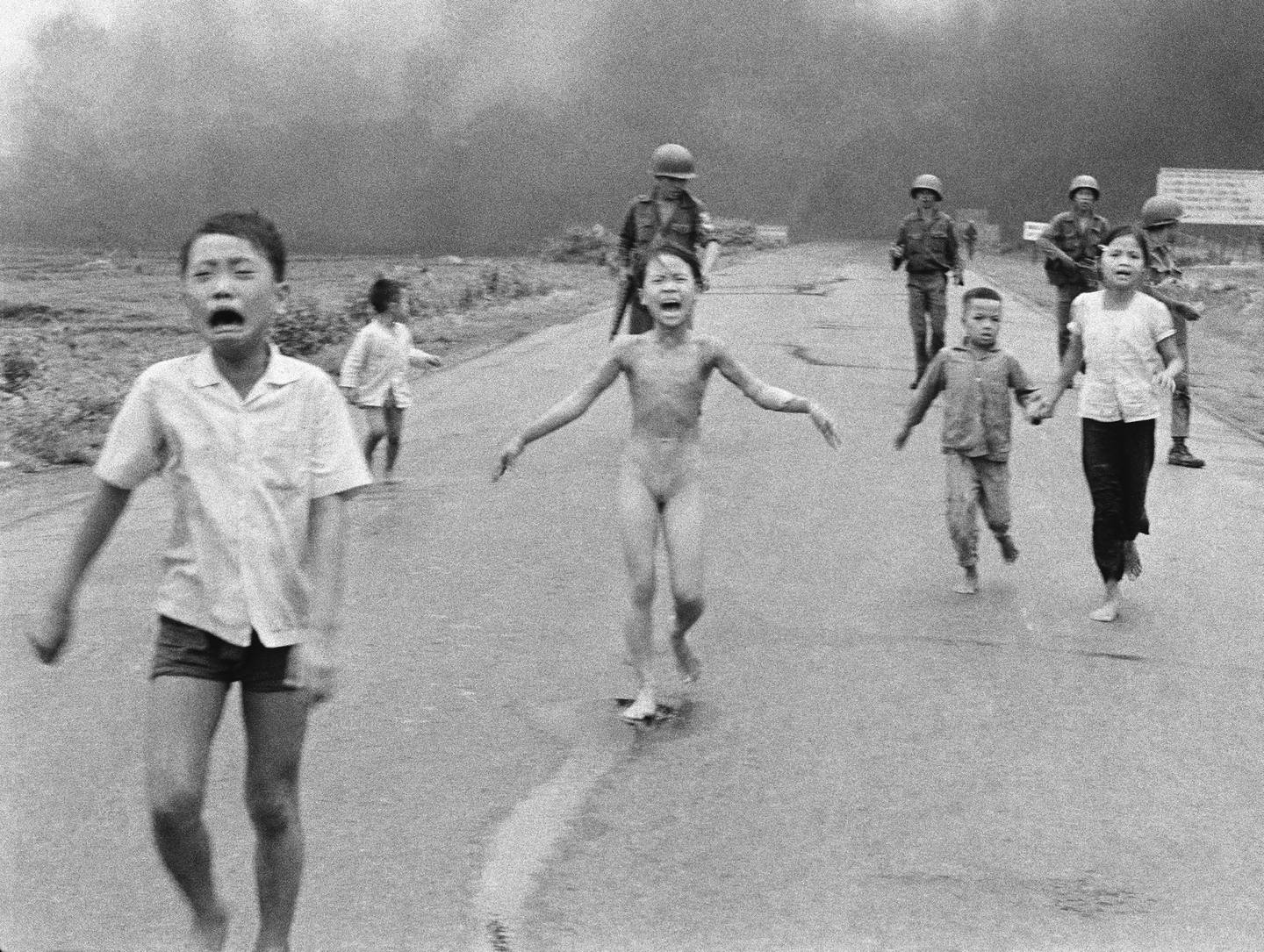 På dette 8. juni 1972, filbildet tatt av Huynh Cong "Nick" Ut, følger sørvietnamesiske styrker bak livredde barn, inkludert 9 år gamle Kim Phuc, midt i sentrum, mens de løper nedover rute 1 nær Trang Bang etter en luftnapalm. angrep på antatte Viet Cong-gjemmesteder. Bildet vant Pulitzer-prisen i 1973 for nyhetsfotografering. Hal Buell, som ledet The Associated Press' fotooperasjoner fra mørkerommets tidsalder inn i digitalfotografiets tidsalder i løpet av en fire-tiårs karriere med nyhetsorganisasjonen som inkluderte 12 Pulitzer-priser og noen av de definerende bildene fra Vietnamkrigen, har dødd. Han var 92. (AP Photo/Nick Ut, File)