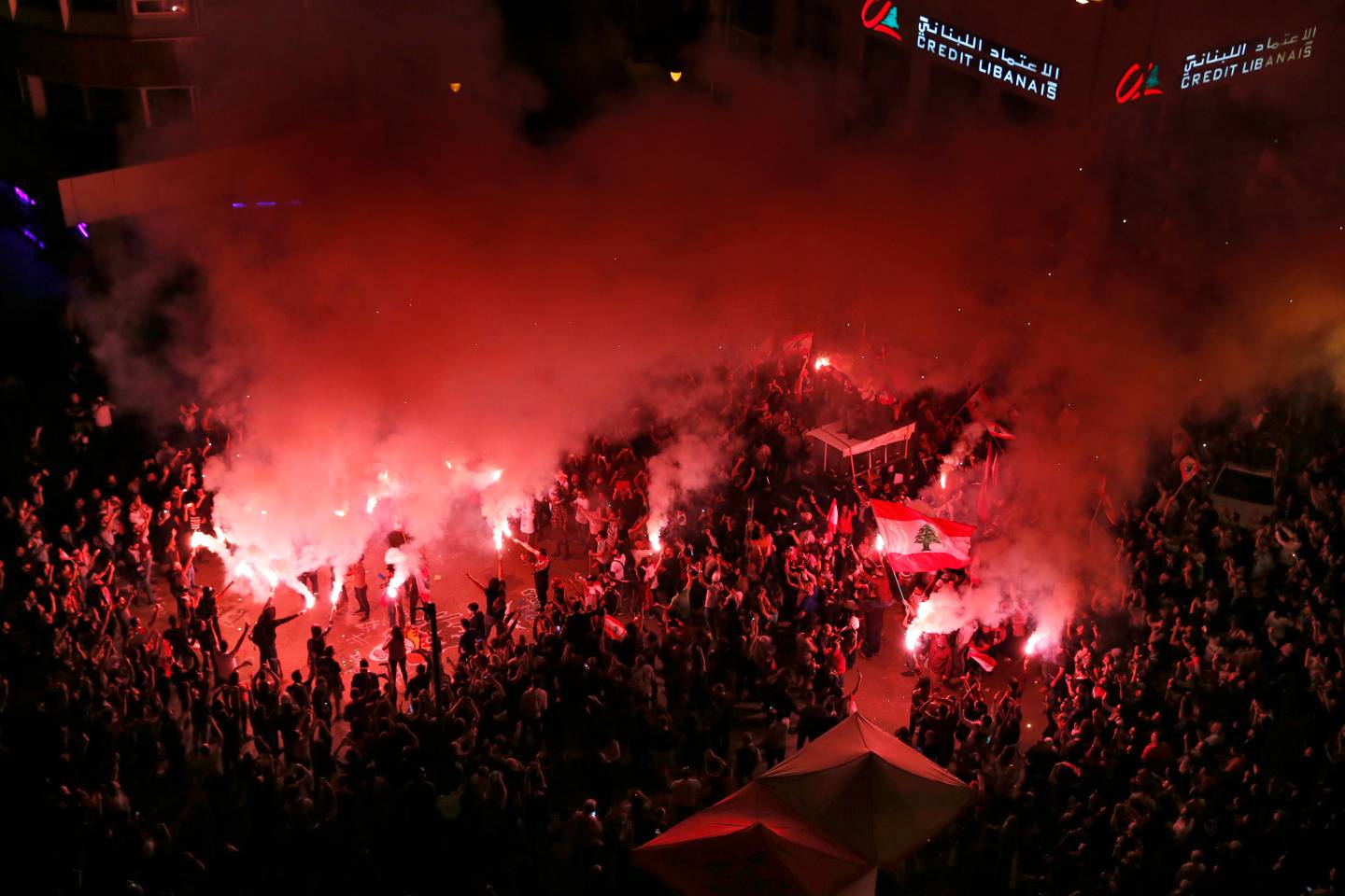 Anti-government protesters light flares and chant slogans against the Lebanese government, in Beirut, Lebanon, Sunday, Nov. 3, 2019. President Michel Aoun and his son-in-law, Foreign Minister Gebran Bassil, have been among the main targets of mass protests that aim to sweep from power Lebanon's entire sectarian and political elite. (AP Photo/Bilal Hussein)
