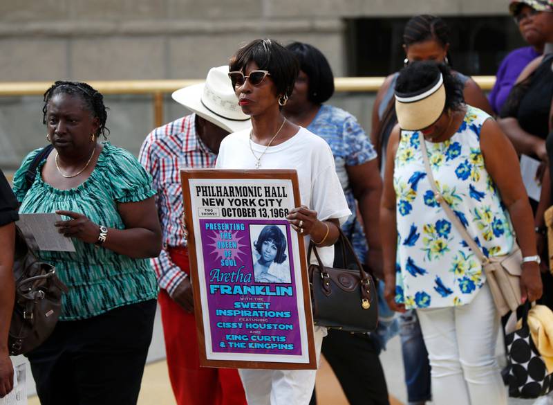 A well wisher carries a sign to view Aretha Franklin's casket at Charles H. Wright Museum of African American History during a public visitation in Detroit, Tuesday, Aug. 28, 2018. Franklin died Aug. 16, of pancreatic cancer at the age of 76. (AP Photo/Paul Sancya, Pool)