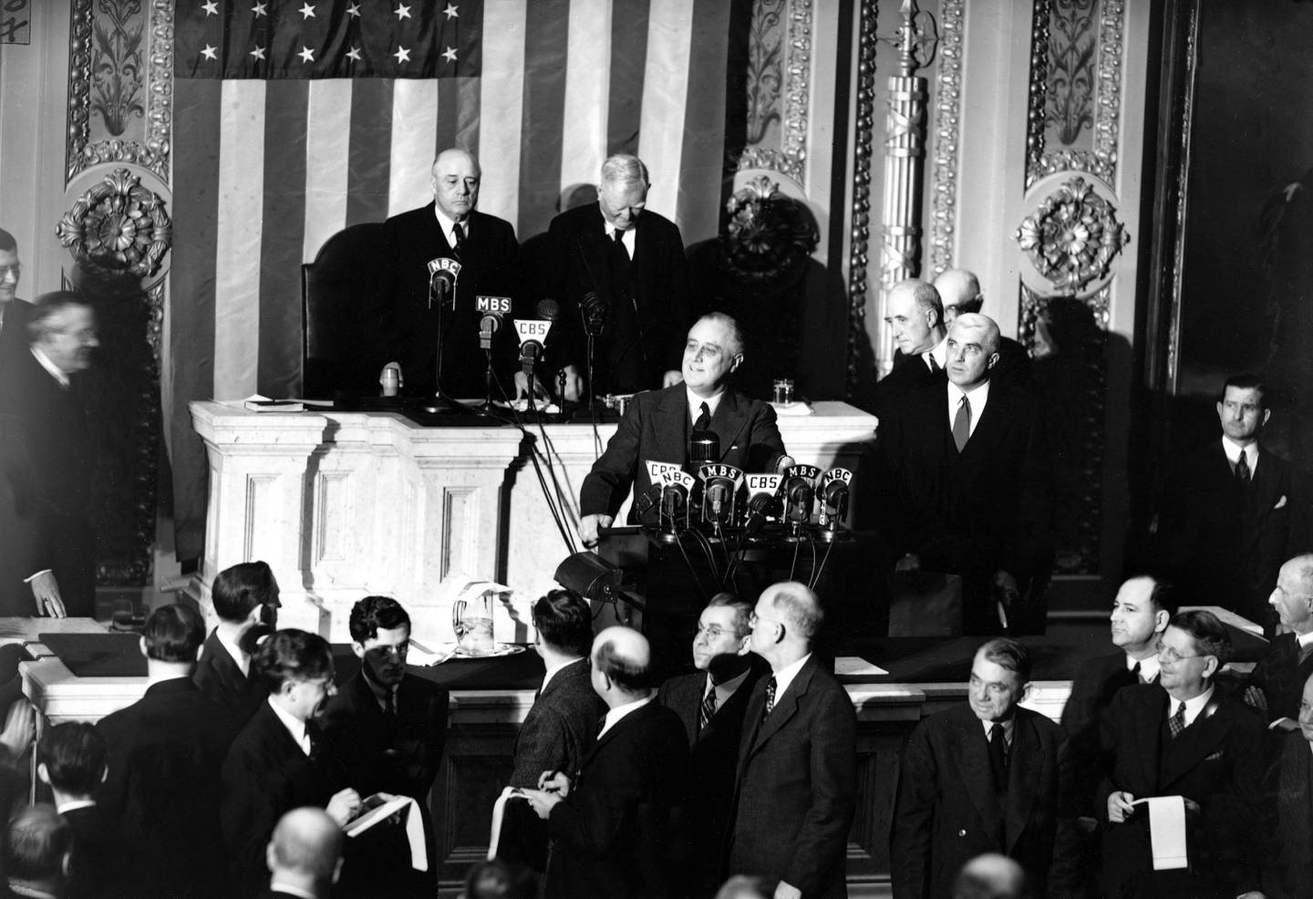 U.S. President Franklin Roosevelt is shown at the rostrum during the first joint session of the 77th Congress for the annual message in Washington, D.C., Jan. 6, 1941.  Standing behind the president are, Vice President John N. Garner, left, and House Speaker Sam Rayburn.  President Roosevelt pleaded for an increase in production of armaments for defense and aid to the fighting democracies.  (AP Photo)