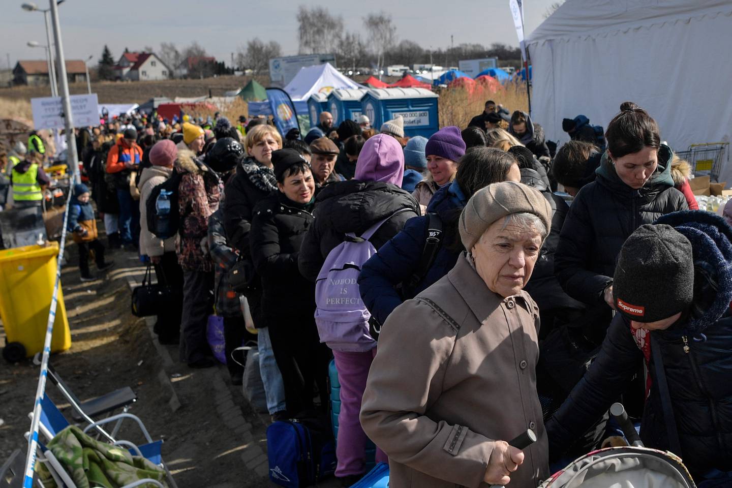 Refugees queue as they wait for further transport at the Medyka border crossing, after crossing at the Ukrainian-Polish border, southeastern Poland on March 12, 2022. - More than two and a half million people have fled the "senseless war" in Ukraine, the UN says -- more than half to Poland. (Photo by Louisa GOULIAMAKI / AFP