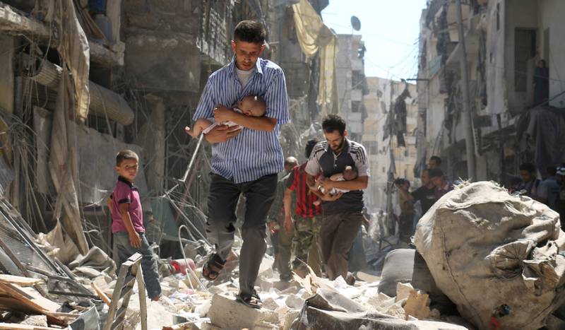 Krigen har begynt på sitt sjuende år. På bildet bærer mennene barn etter et angrep i Aleppo i september i fjor.