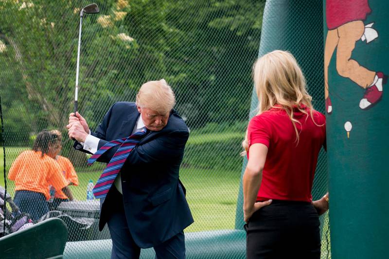 Golfer Natalie Gulbis, right, watches as President Donald Trump swings a golf club during White House Sports and Fitness Day on the South Lawn of the White House, Tuesday, May 29, 2018, in Washington. (AP Photo/Andrew Harnik)