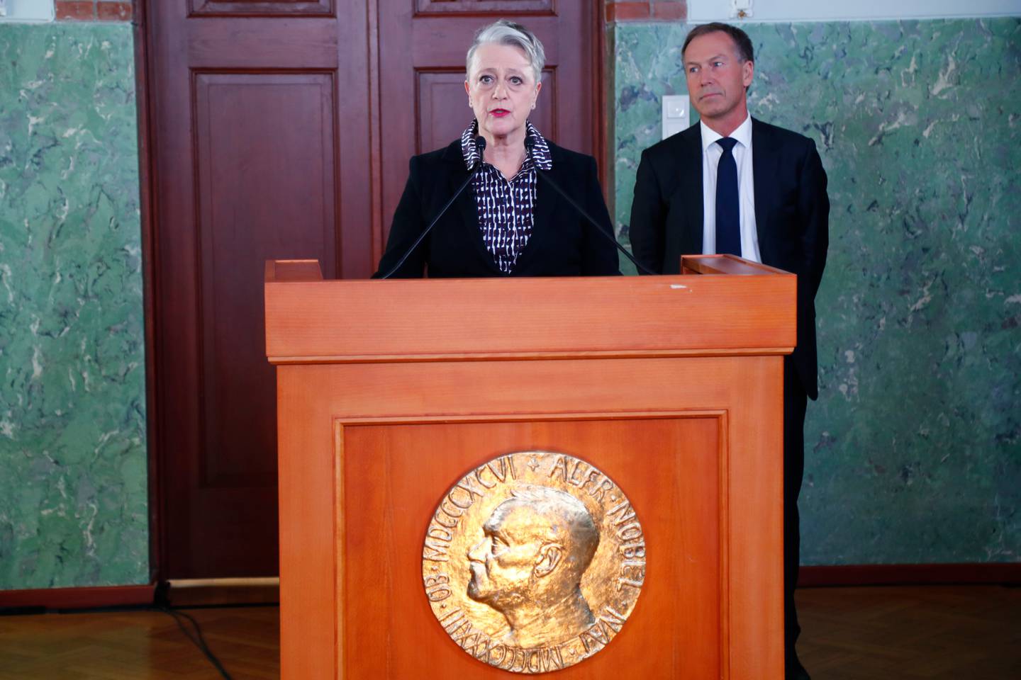 Berit Reiss-Andersen, leder av Nobelkomiteen, og komiteens sekretær Olav Njølstad (i bakgrunnen), offentliggjør vinner av årets fredspris på Nobelinstituttet i Oslo fredag. 