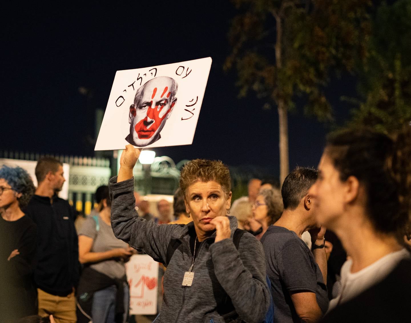 Gymlæreren Rachel holder opp en plakat med bilde av Israels statsminister Benjamin Netanyahu, som har en blodig hånd over ansiktet.