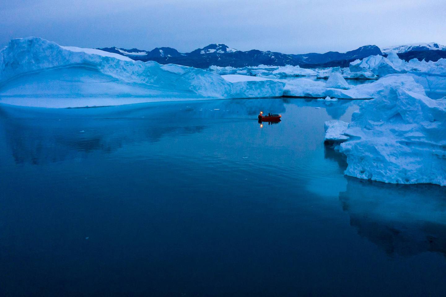 A boat navigates at night between icebergs in eastern Greenland, late Friday, Aug. 15, 2019. Greenland has been melting faster in the last decade and this summer, it has seen two of the biggest melts on record since 2012. (AP Photo/Felipe Dana)