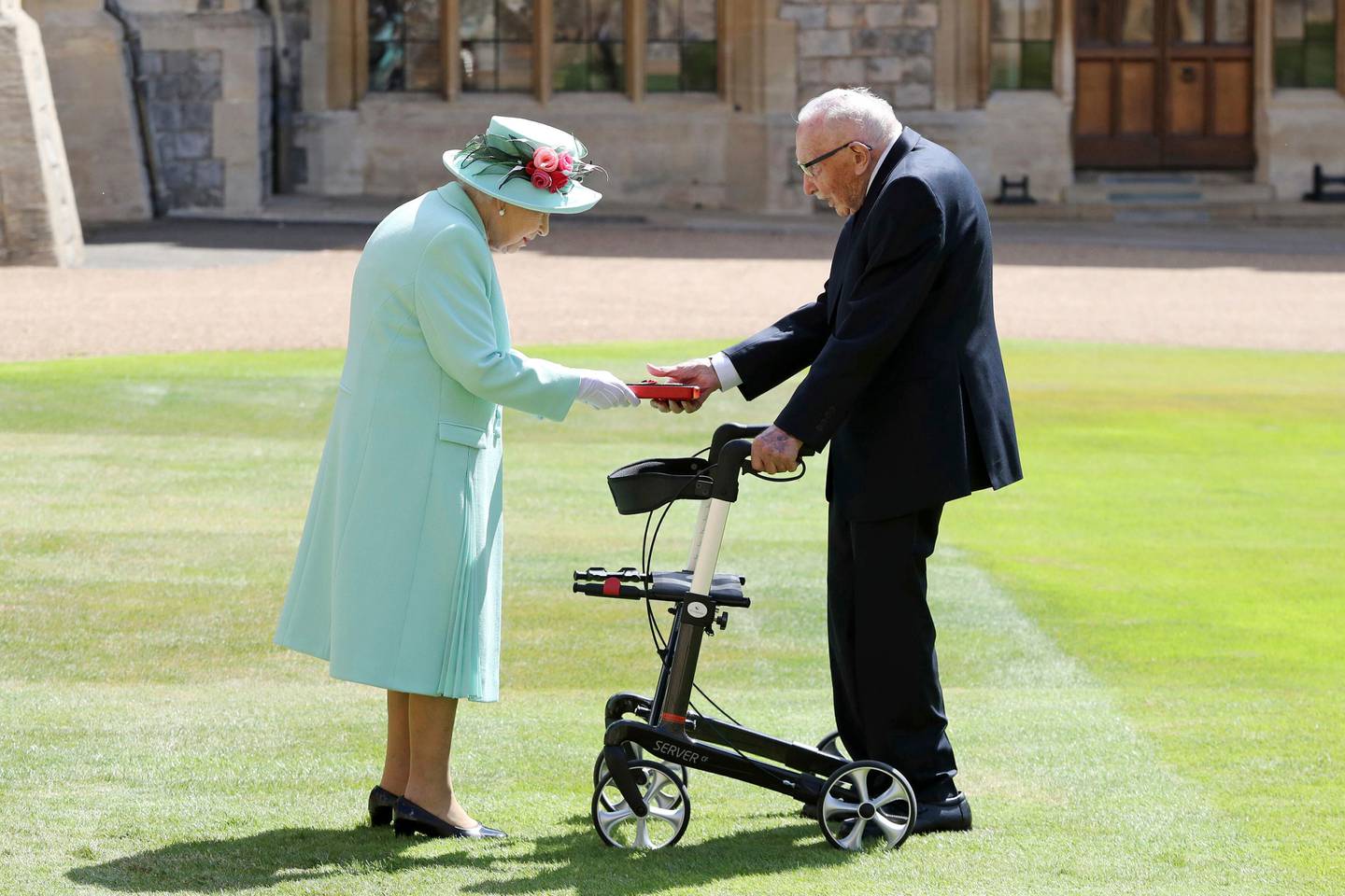 FILE - In this Friday, July 17, 2020 file photo, Captain Sir Thomas Moore receives his knighthood from Britain's Queen Elizabeth, during a ceremony at Windsor Castle in Windsor, England. Tom Moore, the 100-year-old World War II veteran who captivated the British public in the early days of the coronavirus pandemic with his fundraising efforts, has died, Tuesday Feb. 2, 2021. (Chris Jackson/Pool Photo via AP, File)