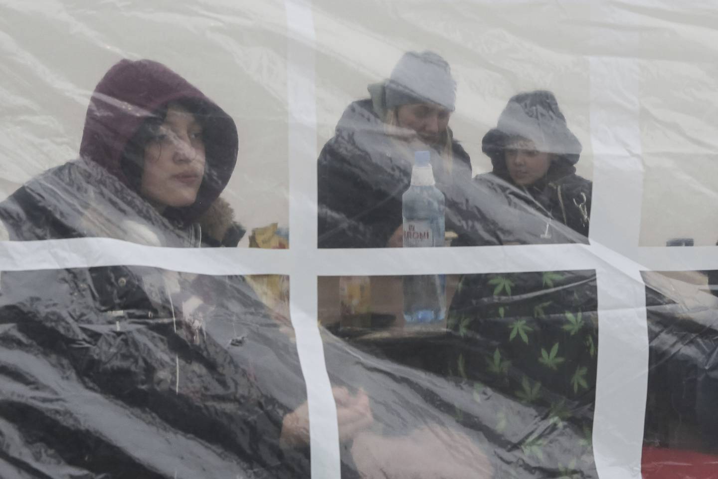 En familie som har flyktet fra Ukraina varmer seg opp i et telt ved grenseovergangen i Medyka, Polen, torsdag.