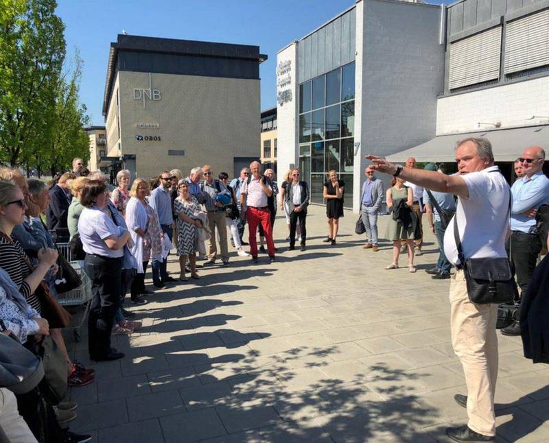 Tom Kristian Hansen peker og forteller hvorfor Leif Tronstads plass i Sandvika er et egnet sted for hovedkontoret til Viken. De 34 medlemmene av fellesnemnda for Viken følger med.