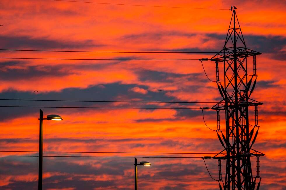 Bildet er av en rødoransje himmel med mørke skyer. Det er en soloppgang. Det er høyspentmaster med strøm på tvers av bildet. Illustrasjonsfoto: Håkon Mosvold Larsen / NTB