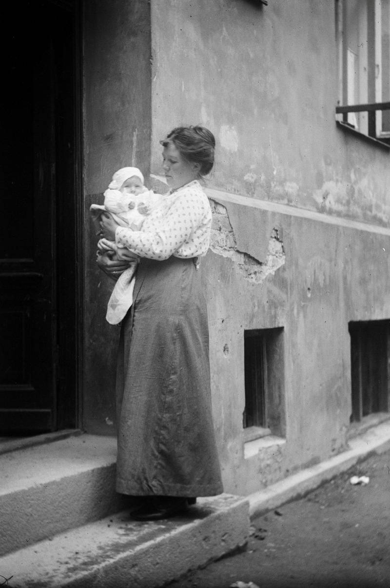 Hvilke mødre fortjente samfunnets støtte? Det var den opphetete debatten ved innføringen av morstrygd fra 1. januar 1920. Kvinne og barn på trapp i bygård, ca. 1915.