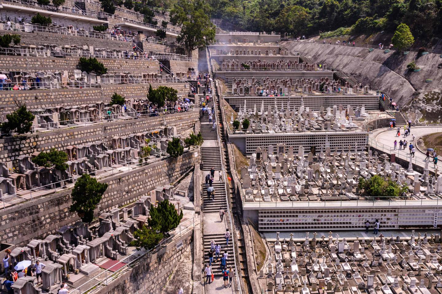TOPSHOT - People walk through a cemetery during the Ching Ming Festival, or grave-sweeping day, in Hong Kong on April 5, 2019. - Visiting the graves of ancestors during Ching Ming is a Chinese tradition dating back 2000 years to the Han dynasty with families paying their respects by cleaning their graves, presenting offerings of food and burning joss paper. (Photo by Anthony WALLACE / AFP)