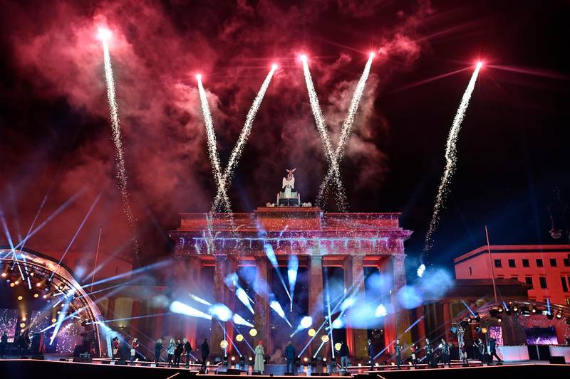 Musicians watch as fireworks explode over Berlin's landmark Brandenburg Gate during the New Year Celebrations in Berlin, Germany, Friday, Jan. 1, 2021. (John MacDougall/Pool Photo via AP)