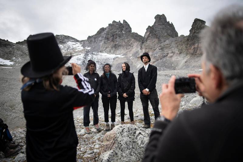 Activists pose in dark clothing in front of the 'dying' glacier of Pizol mountain in Wangs, Switzerland, Sunday, Sept. 22, 2019. Various organizations gathered to shine a light on climate change and melting glaciers. (Gian Ehrenzeller/Keystone via AP)