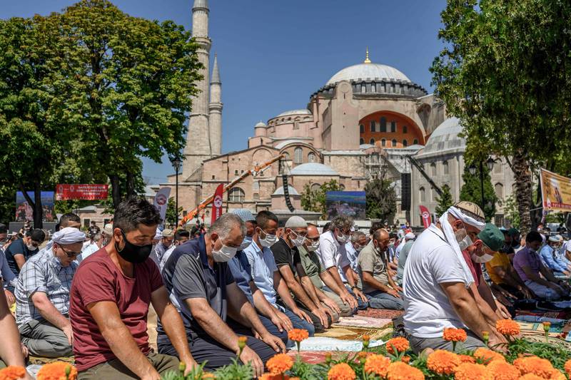 Men perform the Friday prayer on July 24, 2020 outside Hagia Sophia in Istanbul, the first muslim prayer held at the landmark since it was reconverted to a mosque despite international condemnation. - A top Turkish court revoked the sixth-century monument's status as a museum on July 10 and Turkish President then ordered the building to reopen for Muslim worship. The UNESCO World Heritage site in historic Istanbul was first built as a cathedral in the Christian Byzantine Empire but was converted into a mosque after the Ottoman conquest of Constantinople in 1453. (Photo by BULENT KILIC / AFP)