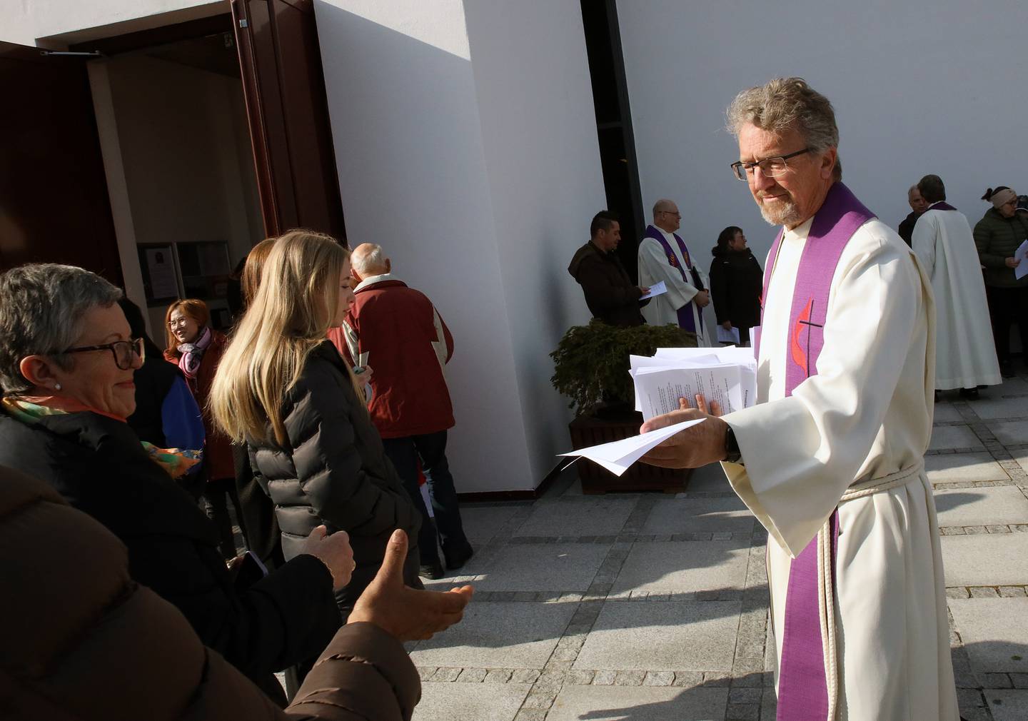 Torgeir Tveter, prest i Metodistkirken, deler ut program til frammøtte.