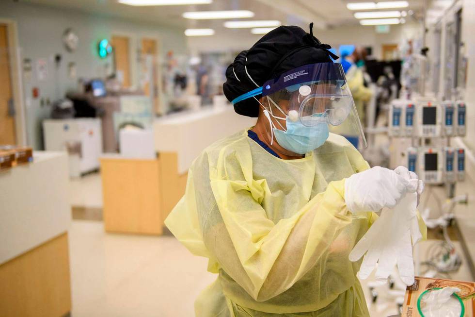 A nurse dons personal protective equipment (PPE) to attend to a patients in a Covid-19 intensive care unit (ICU) at Martin Luther King Jr. (MLK) Community Hospital on January 6, 2021 in the Willowbrook neighborhood of Los Angeles, California. - Deep within a South Los Angeles hospital, a row of elderly Hispanic men in induced comas lay hooked up to ventilators, while nurses clad in spacesuit-looking respirators checked their bleeping monitors in the eerie silence. The intensive care unit in one of the city's poorest districts is well accustomed to death, but with Los Angeles now at the heart of the United States' Covid pandemic, medics say they have never seen anything on this scale. (Photo by Patrick T. FALLON / AFP)