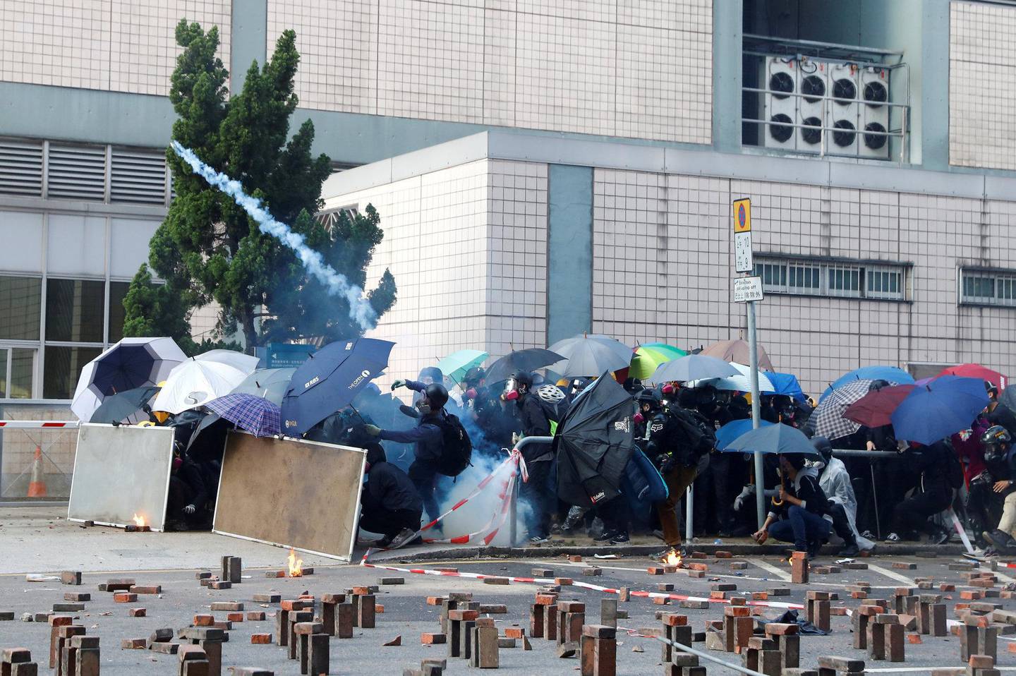 Sammenstøt mellom politi og demonstranter, som beskytter seg med paraplyer, mandag. Foto: NTB scanpix
