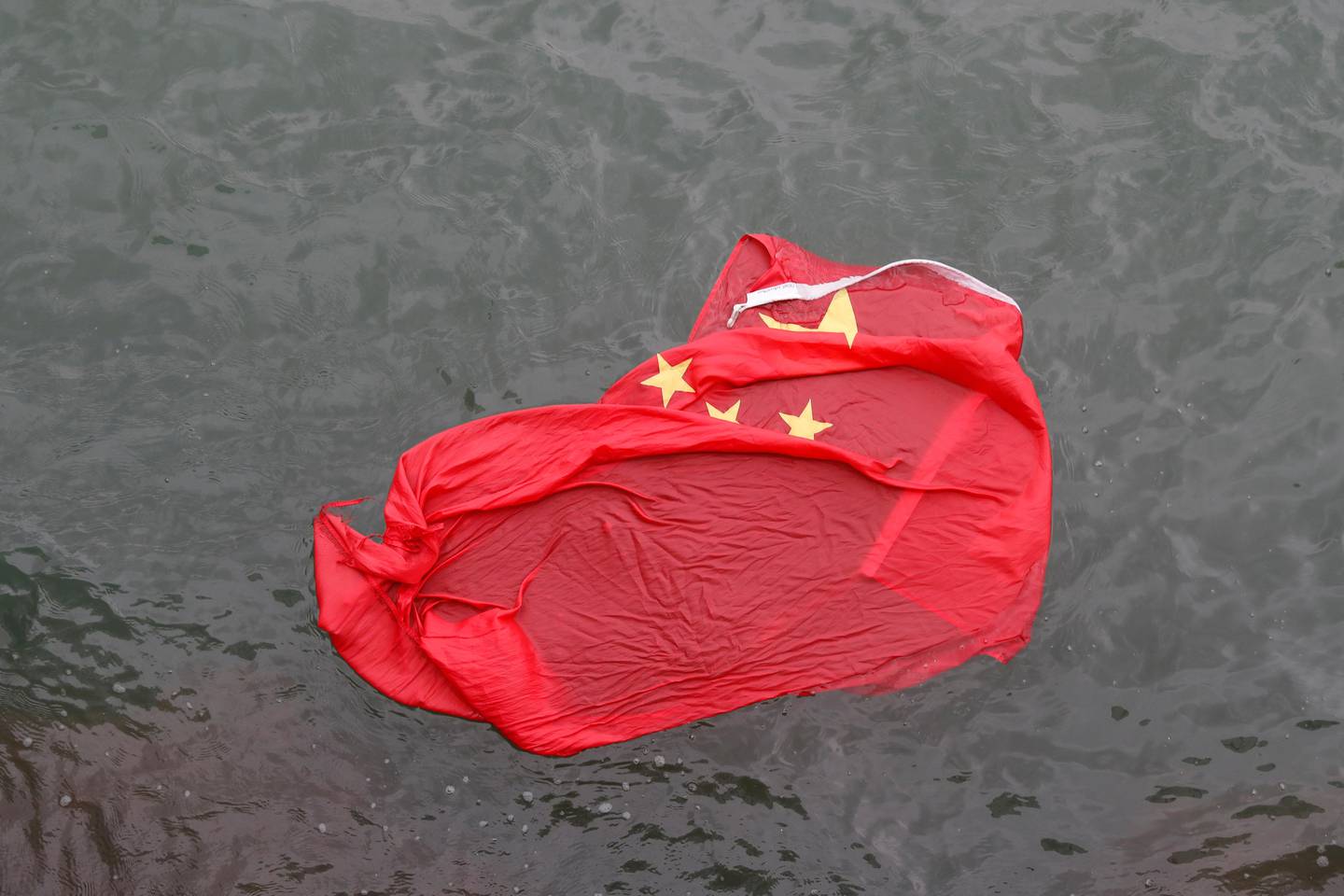 A Chinese flag floats on the surface it was thrown in the water by protesters during a demonstration in Hong Kong, Saturday, Aug. 3, 2019. Hong Kong protesters ignored police warnings and streamed past the designated endpoint for a rally Saturday in the latest of a series of demonstrations targeting the government of the semi-autonomous Chinese territory. (AP Photo/Vincent Thian)
