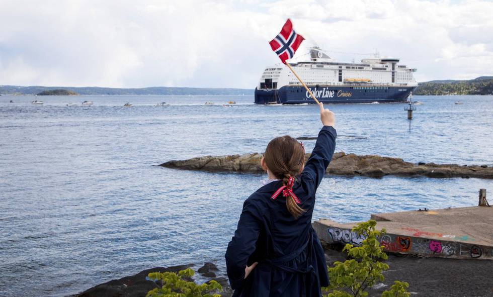 En jente står på Hukodden på Bygdøy i Oslo og med vifter sitt flagg mot fergen Color Magic, 17. mai i fjor. Nasjonaldagen ser ut til å bli annerledes i år også.Foto: Erik Johansen / NTB