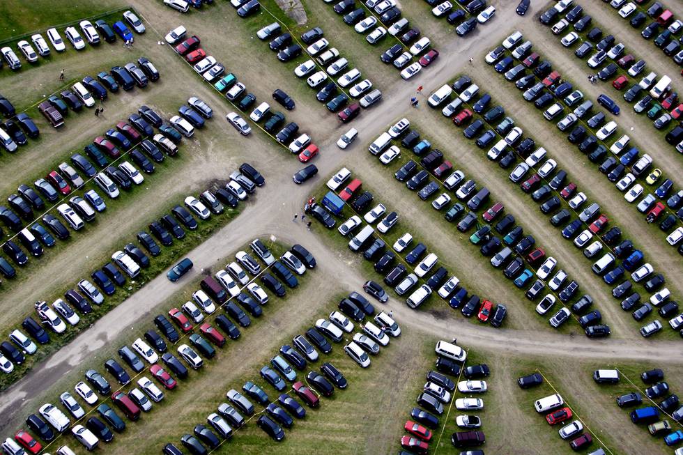 De snart 3 millionene med personbiler i Norge, krever store arealer. Dette bildet viser Ekebergsletta i Oslo fra lufta under Norway Cup for en del år tilbake.