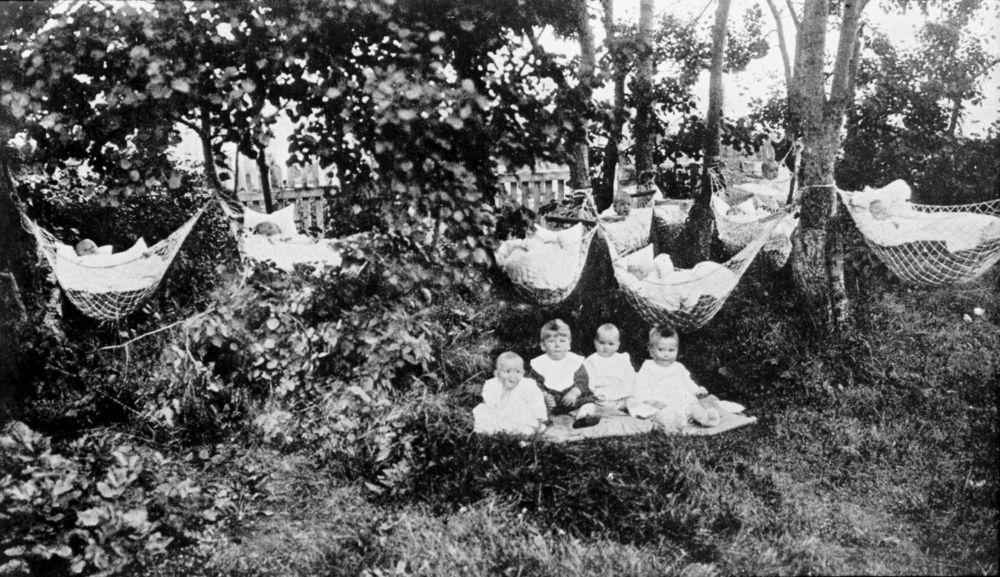 Da Heftyes barnehjem var det behov for et småbarnshjem for midlertidige plasseringer, også av syke barn. Barn hviler i hengekøyer mellom trærne og på gresset på ukjent sted. Bildet er hentet fra Helserådet, overlege Carl Schiøtz' fotosamling.